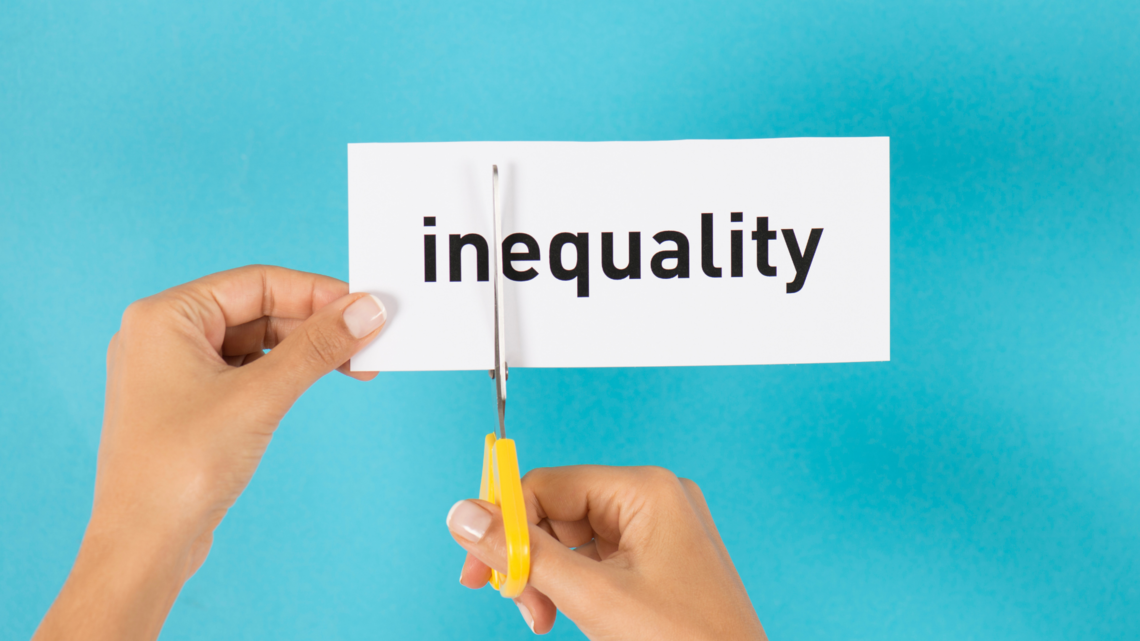 Photo of hands cutting the word inequality with yellow handled scissors